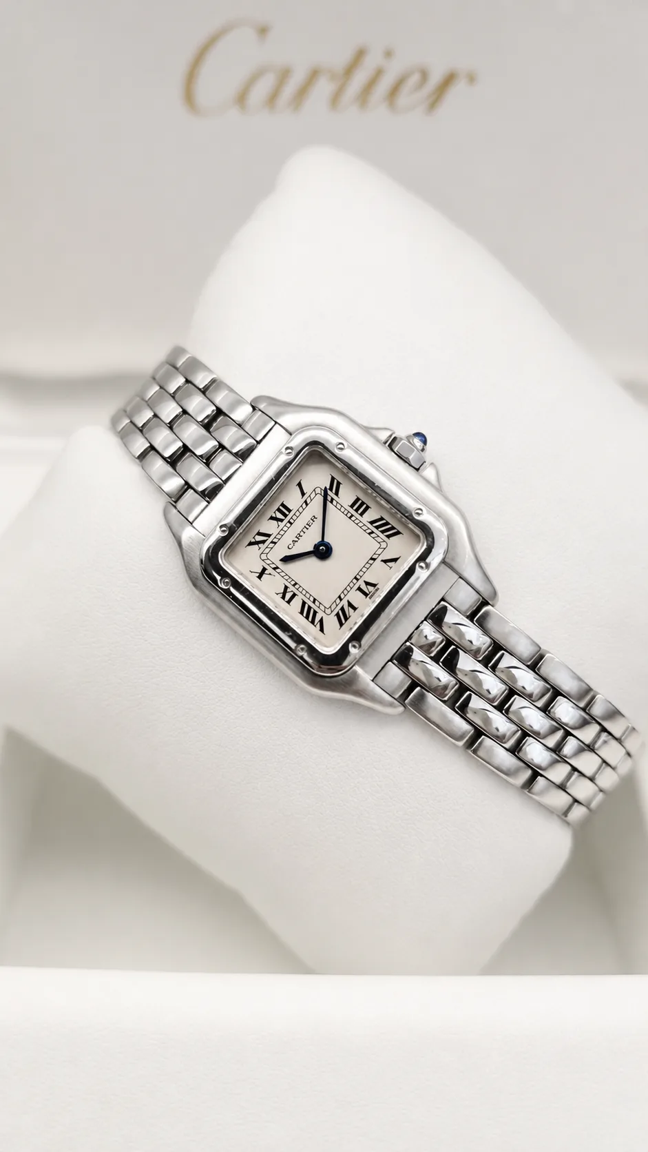 Close-up of a stainless steel Cartier Panthère watch with a white Roman numeral dial and polished link bracelet.